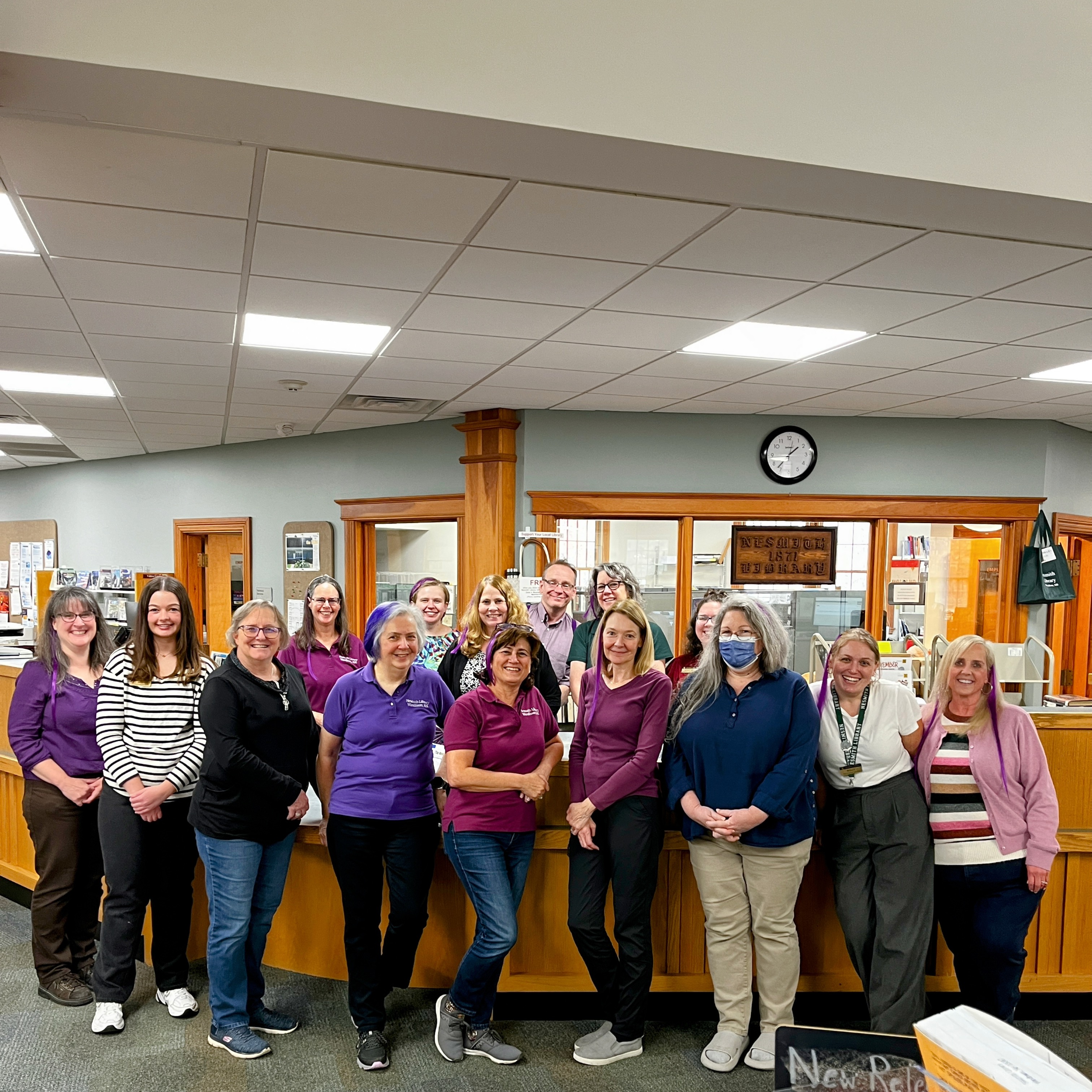 The Nesmith Library staff standing in front of the Circulation desk