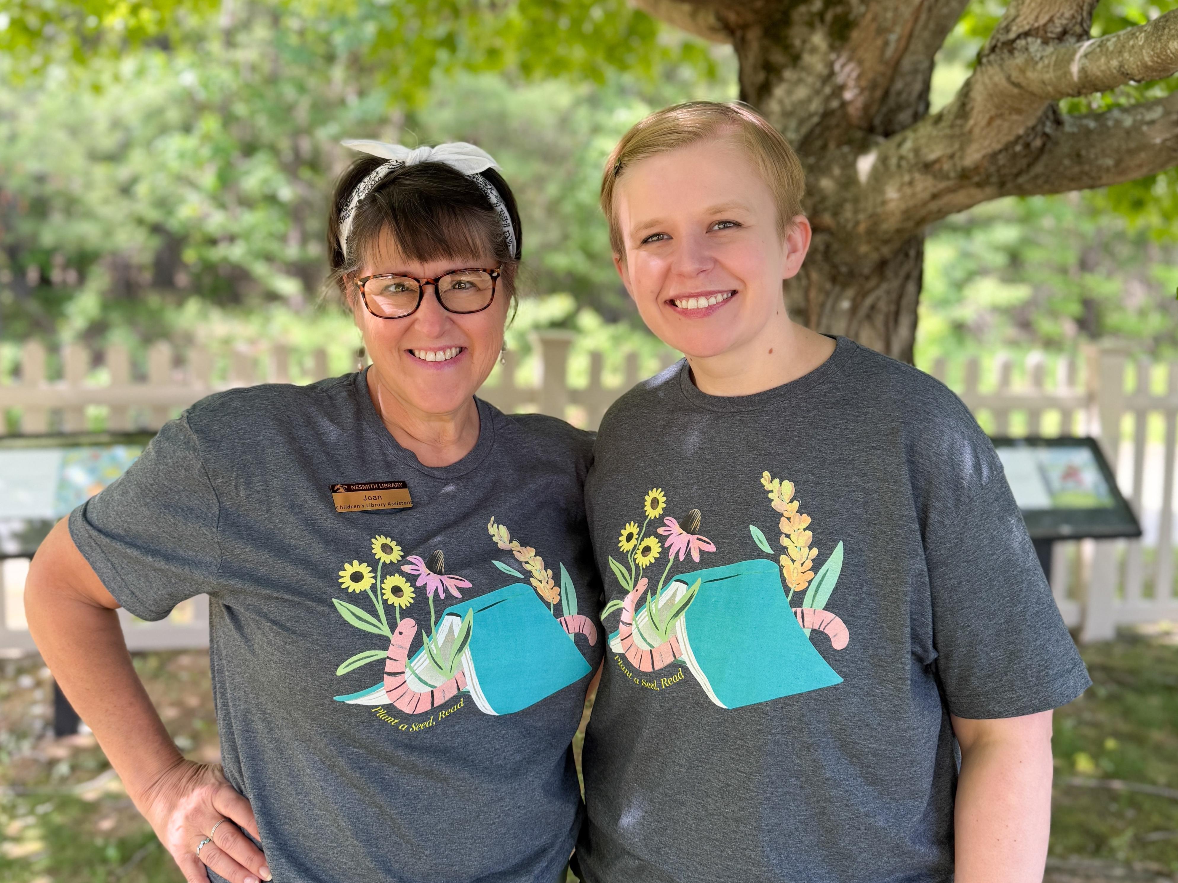 Joan & Azra smiling under a tree in the story garden. 