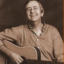 Photo of Irish folk-singer Tom O'Carroll holding a music instrument, smiling